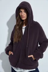 Canguro de corderito con capucha, cierre frontal y bolsillos laterales. Diseño relajado y textura suave.
