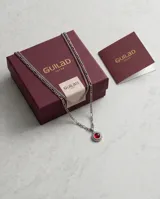 Collar de acero con diseño de doble cadena y dije circular con piedra central roja rodeada por un detalle trenzado.