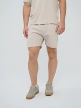 Bermuda Umbro de hombre, color beige, confeccionada en tejido de algodón con bolsillos laterales y cintura elástica con cordón de ajuste.
