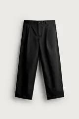 Pantalón relaxed fit de algodón color negro, con pliegues frontales en la cintura, bolsillos laterales y cierre frontal con cremallera y botón.