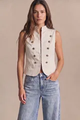 Chaleco de algodón peinado color marfil, de corte entallado al cuerpo, con cuello mao, sin mangas y diseño de doble botonadura con botones metálicos decorativos dorados.