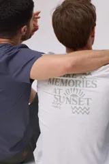 Remera gris melange de manga corta y cuello redondo, con estampa en la espalda en tonos verdes con la frase "Make memories at sunset" y logo Legacy.