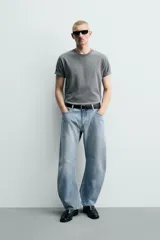Jeans de denim de algodón en color negro con efecto lavado, corte amplio y silueta curva tipo barrel fit con pinzas en las rodillas. Presenta diseño clásico de cinco bolsillos y cierre frontal con cremallera y botón metálico.