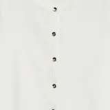 Chaqueta de punto blanca con cuello redondo y cierre frontal con botones.