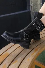 Bota corta de cuero negro con hebillas y cierre lateral.