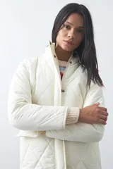 Campera capitoneada de largo medio, color negro, con cuello alto, cierre frontal con cremallera y broches a presión, y bolsillos laterales con solapa.