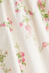 Vestido corto de popelina de algodón, color blanco con estampado floreado en tonos rosados y verdes, escote cuadrado con cordón ajustable, mangas cortas abullonadas y pollera acampanada.