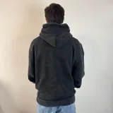 Canguro negro con capucha, corte oversize, con un diseño abstracto en el pecho.