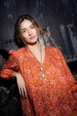Camisa de seda con estampado floral en tonos naranjas y rosados, de corte amplio y estilo boho. Presenta mangas largas abullonadas, frunces en hombros y espalda, y cierre frontal con botones.