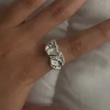 Anillo plateado con diseño irregular y abertura ajustable.