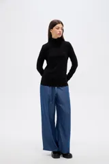 Polera de lyocell color negro, con cuello alto y ajuste al cuerpo, de manga larga.