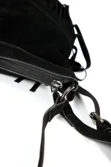 Cartera de gamuza negra con diseño de flecos largos en la parte inferior y detalle de hebilla metálica estilo western en el centro. Cuenta con correa larga ajustable para llevar al hombro o cruzada.