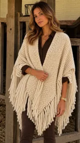 Ruana de lana Merino color camel, con diseño triangular, tejido texturizado y maxi flecos en los bordes.