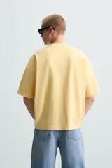 Camiseta gris de corte cuadrado y holgado, con cuello redondo y mangas cortas.