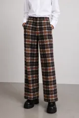 Pantalón de vestir de pierna ancha con estampado tartán en tonos marrones, negros y blancos, con bolsillos delanteros y cierre frontal con botón.