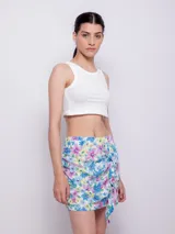 Minifalda estampada con flores en tonos celeste, azul, rosa y amarillo, con volados en el frente y cierre invisible en la parte trasera.