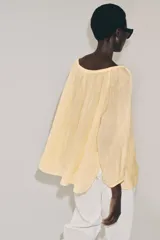 Blusa de lino color blanco, con escote recto ajustable mediante cordón y hombros descubiertos. Cuenta con manga larga abullonada terminada en elástico.