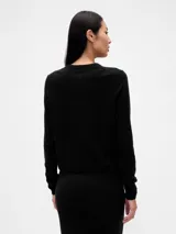 Saco de punto fino color marfil, con cuello redondo, cierre frontal con botones y mangas largas.