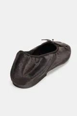Zapato tipo bailarina de efecto terciopelo en color marrón oscuro, con detalle de lazo en la parte delantera y punta redonda.