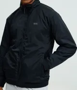 Campera deportiva reversible de manga larga con cierre frontal de cremallera, cuello alto y bolsillos laterales. Confeccionada en poliamida con forro interior de fleece, presenta un pequeño logo estampado en el pecho.
