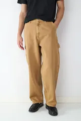 Pantalón estilo carpintero de corte holgado, color camel, con bolsillos laterales funcionales y cierre frontal de botón.