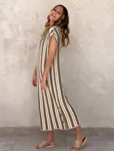 Vestido midi de punto sin mangas, con cuello en V acanalado y diseño de rayas verticales en tonos beige y marrón. Presenta aberturas laterales decoradas con botones a lo largo del ruedo.