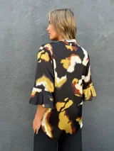 Blusa de satén con escote en V y mangas tres cuartos acampanadas, con estampado abstracto en tonos negro, caramelo, verde lima y blanco.