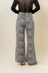 Jean de tiro medio a alto con estampa de cebra en blanco y negro, de corte wide leg. Posee bolsillos funcionales delanteros y traseros, y cierre frontal con botón.