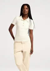 Remera polo de manga corta, color blanco, de corte ajustado con cuello camisero y cartera de tres botones frontales.
