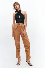 Pantalón de lino color marrón claro, con corte recto, cintura alta con lazo ajustable, elástico en la parte trasera de la cintura, bolsillos laterales y presillas en las piernas.