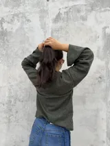 Polera de punto acanalado en color verde oliva, con cuello alto abierto lateralmente y mangas largas amplias. Presenta un diseño de corte recto y holgado.