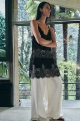 Top largo confeccionado en tejido de encaje con escote en pico y tirantes finos. Presenta una combinación de tejidos a tono con diseño sofisticado.