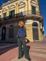Camisa de jean azul oscuro con cuello estilo marinero y puños con volados, ambos con ribetes en color rojo. Presenta cierre frontal con botones rojos.