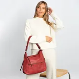 Cartera de hombro color negro, confeccionada en material símil cuero con textura granulada. Presenta un diseño estructurado con cierre superior, bolsillo frontal con cierre horizontal, bolsillos laterales con cierre y herrajes metálicos. Incluye una correa de hombro fija y una correa larga regulable extraíble.