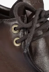 Zapato tipo Oxford de cuero color marrón con efecto desgastado, cordones al tono y taco ancho cuadrado.