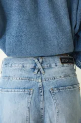 Jean de tiro medio con silueta amplia y corte baggy, confeccionado en denim de algodón con lavado claro desgastado. Cuenta con cierre frontal, botón metálico y bolsillos funcionales.