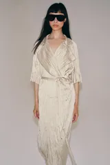 Vestido midi de Zara Woman Collection color beige, con cuello solapa, mangas por debajo del codo y diseño cruzado. Confeccionado en tejido plisado con brillo satinado, incluye un cinturón ajustable del mismo género con lazada en la cintura.