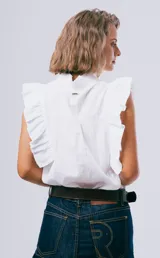 Blusa sin mangas color blanco con cuello alto con volados y detalles de volados en los hombros. Cuenta con cierre frontal de botones.