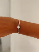 Pulsera de acero quirúrgico en tono plateado con cadena de eslabones tipo ratón y dije central en forma de trébol con centro blanco.