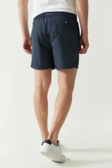 Short de baño liso con cintura elástica y cordón ajustable. Cuenta con dos bolsillos laterales, un bolsillo trasero y logo bordado. Confeccionado en tela ligera de secado rápido.