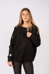 Sweater negro de corte holgado con cuello redondo y mangas largas. Presenta detalles de botones metálicos dorados a lo largo de los hombros y las mangas.
