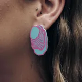 Aros colgantes con forma de cono de color celeste con líneas onduladas rosas.