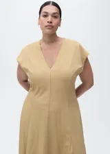 Vestido midi de corte evasé en color beige, con cuello en pico y manga corta. Presenta un diseño con costuras verticales decorativas y cierre de cremallera en la parte posterior.