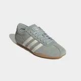Championes Adidas modelo Tokyo, de diseño retro y corte bajo. Confeccionados en gamuza color verde grisáceo con las icónicas tres tiras laterales en color crema y suela de caucho color caramelo.