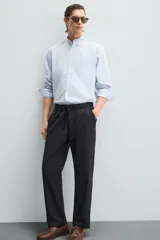 Pantalón de corte relajado color beige confeccionado en tejido de mezcla de algodón y lino. Posee cintura elástica ajustable con cordón, bolsillos frontales y bolsillos traseros de vivo.