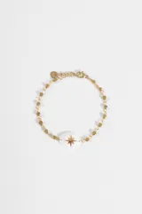 Pulsera dorada de acero quirúrgico con dije central ovalado de nácar blanco con una estrella dorada grabada. La cadena presenta eslabones intercalados con cuentas facetadas.