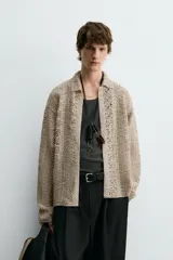 Sobrecamisa de hombre color beige, confeccionada en tejido de crochet con estructura abierta, cuello solapa, manga larga y cierre frontal de botones.