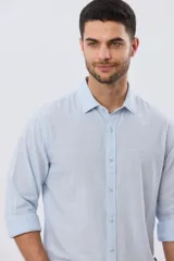 Camisa de manga larga confeccionada en mezcla de lino y algodón, con sutiles rayas celestes, cuello camisero clásico y cierre frontal de botones.