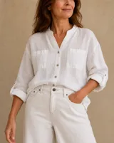 Camisa blanca de lino, con cuello mao, escote en V, mangas largas con presilla para arremangar y dos bolsillos frontales con solapa.