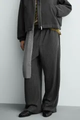 Pantalón de corte baggy fit, color gris oscuro con estampado de rayas verticales finas. Presenta cintura elástica con cordón interior, bolsillos frontales de vivo y bolsillos traseros de plastrón.